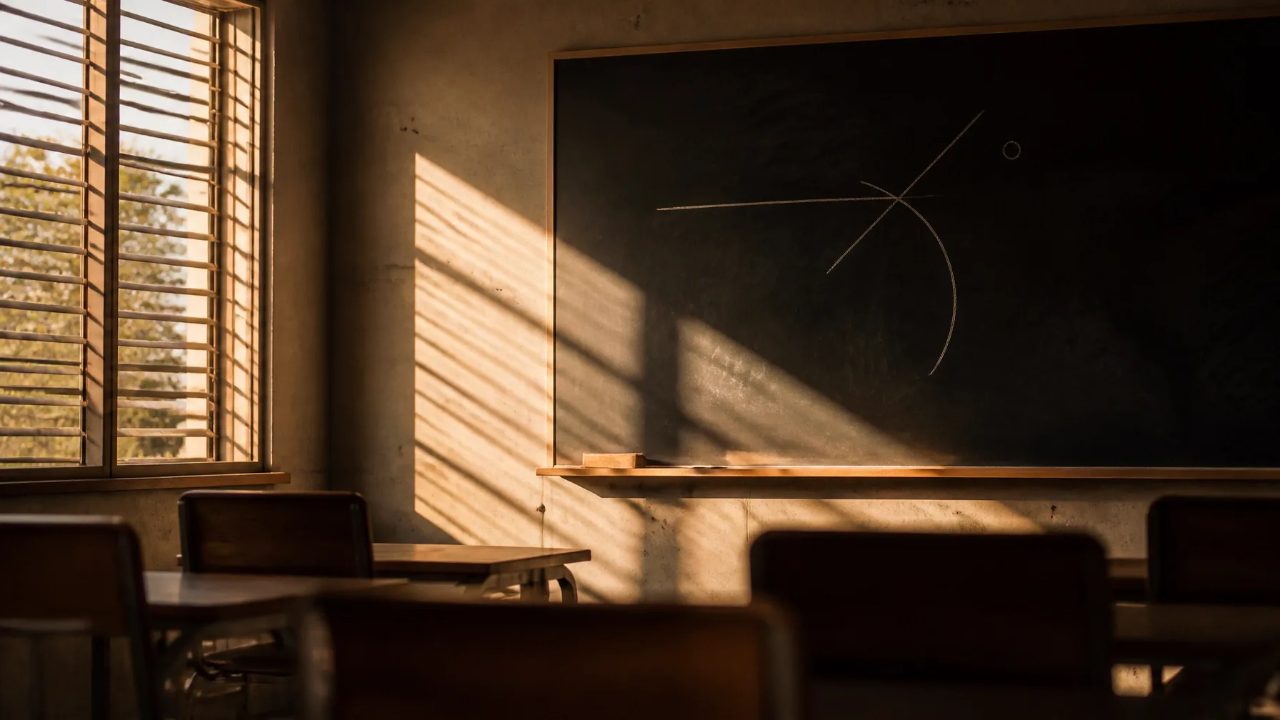 Sala de aula vazia com quadro de giz, esquema incompleto e luz dourada no fim da tarde